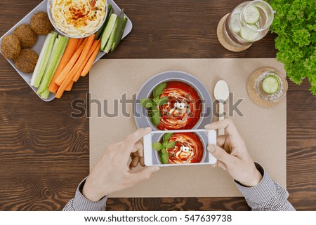 Man taking picture of tomatoe cream soup