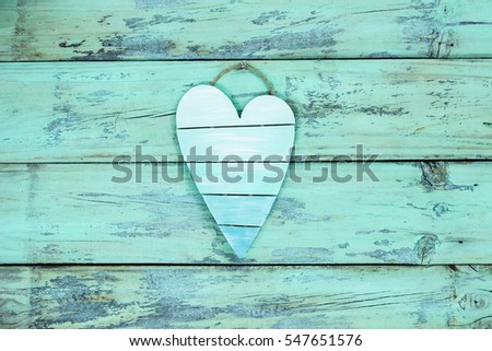 Blank country broken heart hanging on antique mint green rustic wood door; Valentine's Day and love concept background with wooden painted copy space