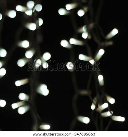 Soft abstract bokeh background. Blurry Luminous garlands of electric lights. The gentle tone purple, orange. Dark night. Festive party. Christmas. New Year.