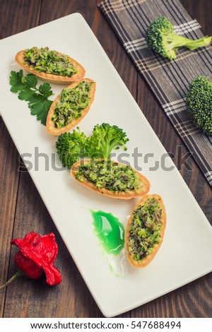 Tartlets stuffed with minced meat  broccoli and tuna. Wooden background