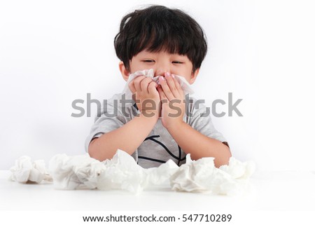 Sick little Asian boy wiping or cleaning nose with tissue isolated white background Royalty-Free Stock Photo #547710289
