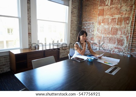 Businesswoman Studying Document In Boardroom
