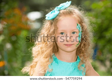 Beautiful happy girl kid with aqua make-up on birthday in park. Celebration concept and childhood, love
