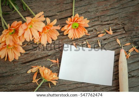 Orange flowers with a note on the old wooden table background in vintage style