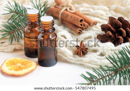 Essential oil blend. Dark glass bottles, cinnamon, pine twigs, dried citrus slice, anise, woolen wrap. Natural home deodorants. Warm toned.  Royalty-Free Stock Photo #547807495