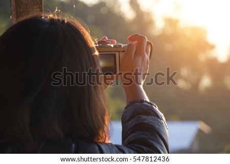 A woman photographs the sun is about to fall.