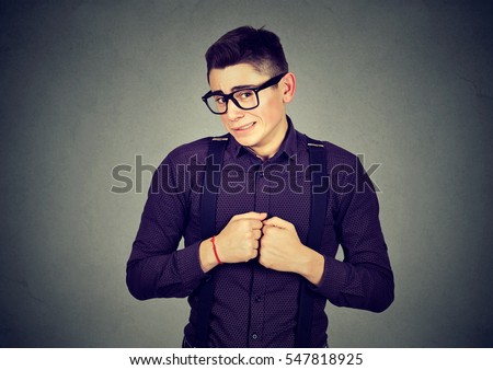 Portrait young man in unpleasant awkward situation playing nervously with hands isolated on gray background. Negative emotions Royalty-Free Stock Photo #547818925