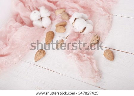 almonds and cotton with rose textile on white wooden table. 