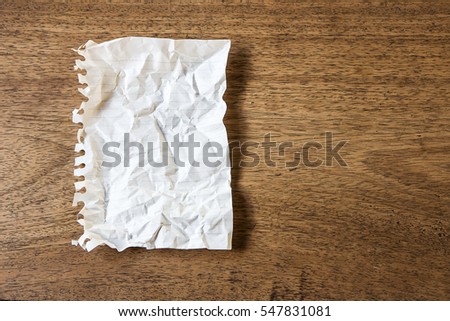Wrinkled sheet of white paper on wood