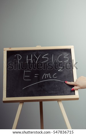 Handwritten physics word and formula E=mc2 on chalkboard, gray background
