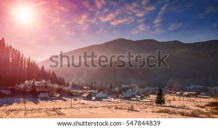 Wonderful winter landscape. Frosty sunny morning over the mountain valley, with colorful sky on the background. fog over the hills, under the influence of sunlight. Christmas holiday concept