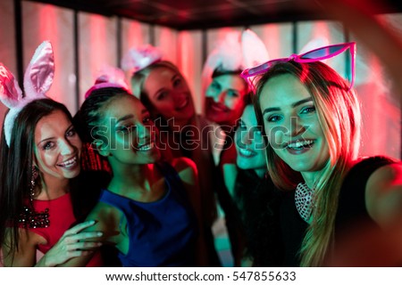 Group of smiling friends posing for selfie in bar