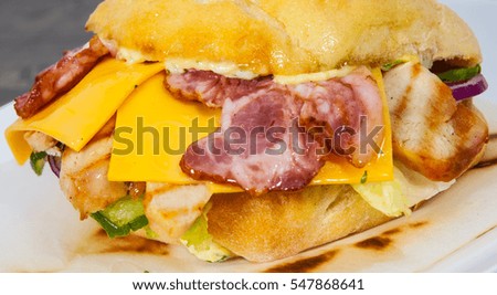 fast food. burger with meat, tomato, onion, cheese, lettuce, bacon on wooden table