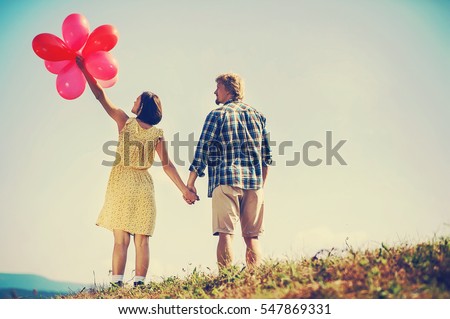 happy couple of man and woman in love dressed in country style holding red balloon. vintage picture