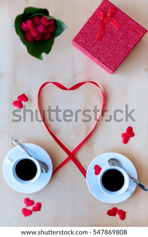 Couple white cups with coffee, gift box decorated by red ribbon on wooden table. Valentine's day celebration concept. Copyspace. Vertical composition. Top view.