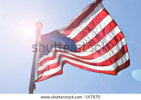 United States Flag waving in the wind with sun behind
