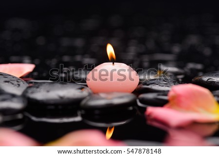 Still life with orange rose, petals with candle and therapy stones 
