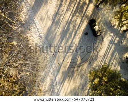 aerial view of snowy forest in sunny winter day with country road. drone photography