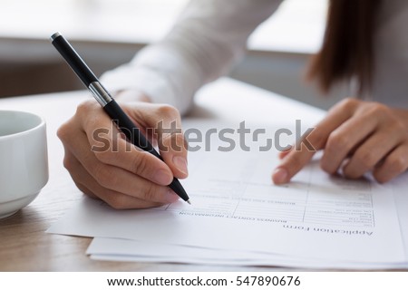 Closeup of Woman Completing Application Form Royalty-Free Stock Photo #547890676