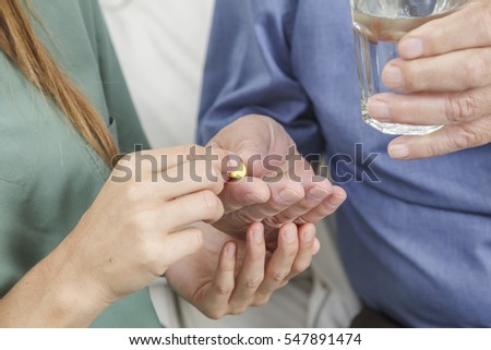 Senior man taking his medication under the guidance of his nurse in retirement home