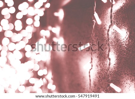 Soft colorful bokeh background. Luminous garlands of electric lights. Stone wall. Copy space to add text. Unsaturated colors. Blurry abstraction. Gentle turquoise,green tone. Dark night.Festive party.