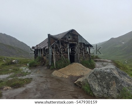 Abandoned cabin in an isolated spot with mountains on each side. Royalty-Free Stock Photo #547930159