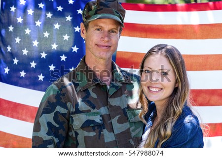 Portrait of american soldier reunited with his partner in front of american flag