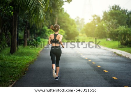 Young fitness sport woman running on the road in the morning, Sun light flare , Selective focus