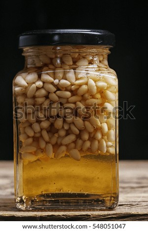 closeup nuts and honey in the pot on a dark background studio