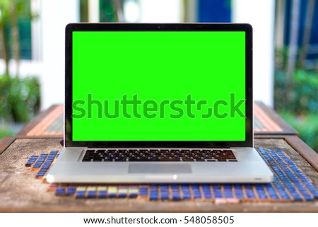 Mockup image of green screen display laptop computer,cup and diary on wood table at coffee shop background for business