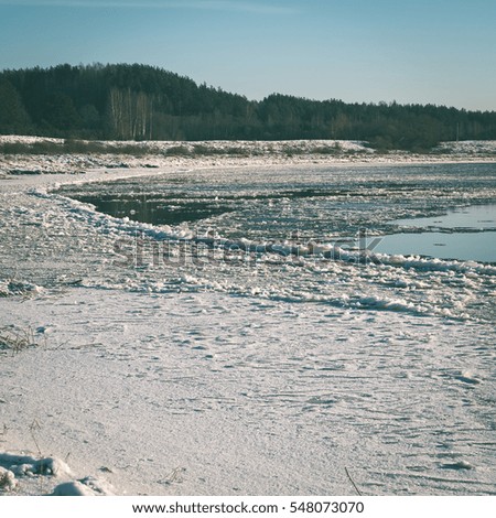 beautiful snowy winter landscape with frozen river and blue sky - instant vintage square photo