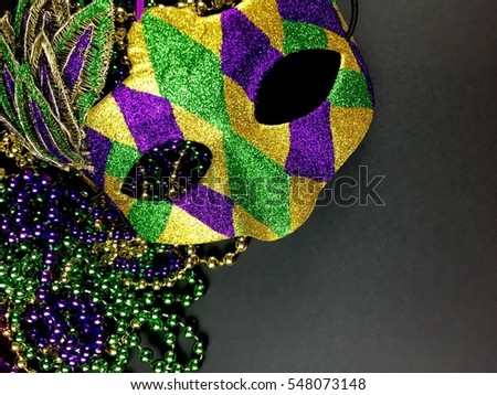 Maris gras mask and beads on a black background with copy space