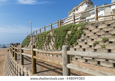 Retaining wall and wooden barrier on  empty beach against blue skyline and residential buildings on beach in Ballito near Durban, South Africa