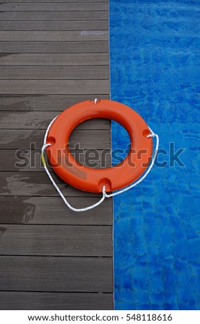 Orange life buoy on wooden deck near swimming pool