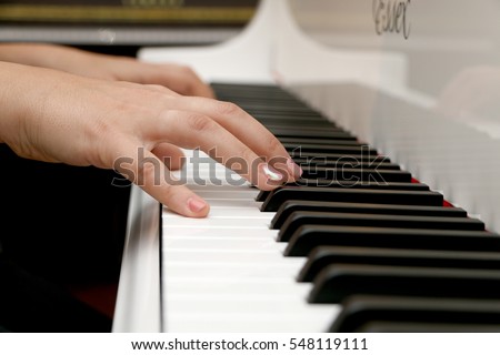 The girl playing the piano, close-up piano, white and black keyboard