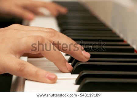 The girl playing the piano, close-up piano, white and black keyboard