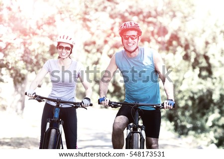 Couple smiling and posing with their bikes on the wood