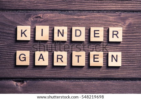 Alphabet letters on wooden pieces collected to word kinder garten