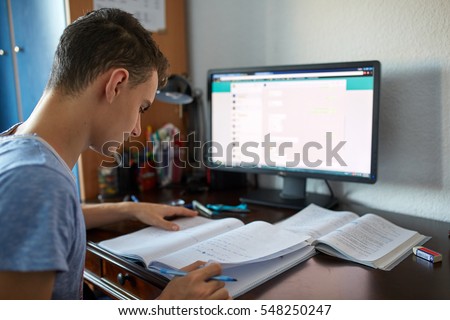 Teenager boy doing homework on his desk at home Royalty-Free Stock Photo #548250247