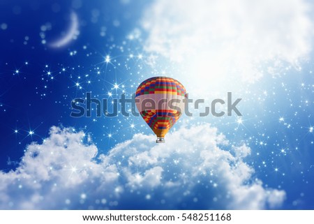 Idyllic heavenly picture - colorful hot air balloon rise up into blue sky with bright stars and new moon. Dream come true concept. Royalty-Free Stock Photo #548251168
