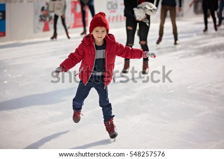 Happy boy with red hat and jacket, skating during the day, having fun Royalty-Free Stock Photo #548257576