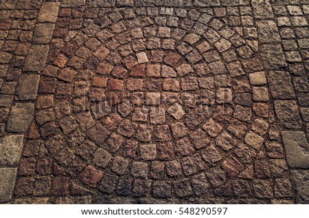 Square shaped cobble stones in a circular pattern from an old city pavement.