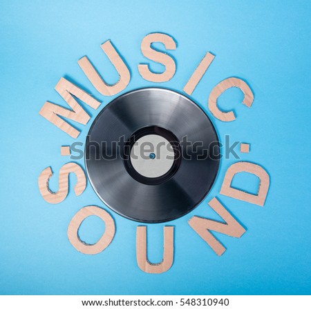 Inscription SOUND made from cardboard letters on a blue background with vinil disk, made photo from top. High definition.