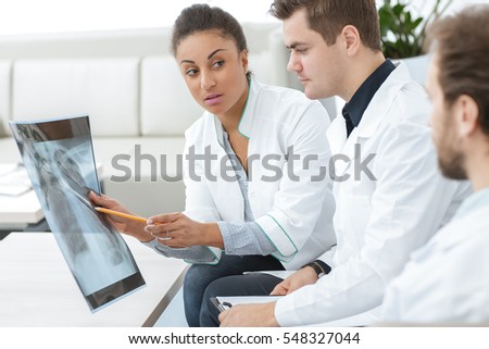 Second opinion. Shot of a female doctor analyzing x-ray scan of the patient with her medical team colleagues at the hospital profession job teamwork communication medicine healthcare concept Royalty-Free Stock Photo #548327044