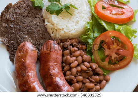 Photo with barbecue, calabresa, beans, rice, lettuce, tomato and coriander