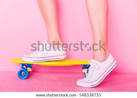 Conceptual shooting of girl's feet standing on the skateboard