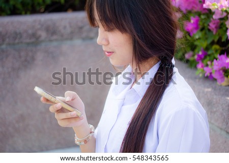 Portrait of thai high school student uniform teen beautiful girl using her phone and smile