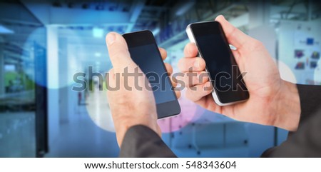 Businessman holding a phone in each hand against illuminated light 3d