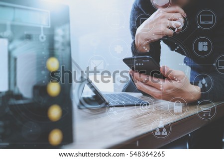 businessman hand using smart phone,mobile payments online shopping,omni channel,digital tablet docking keyboard computer,compact server on wooden desk,virtual interface icons screen
