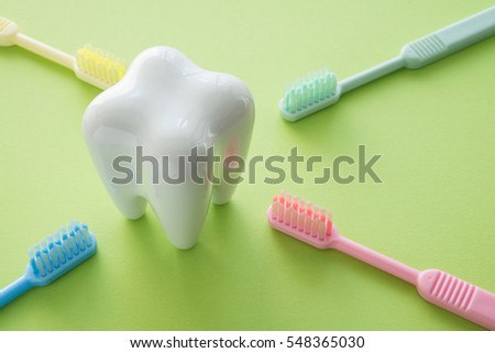White tooth and colorful toothbrush on green background, dental care concept